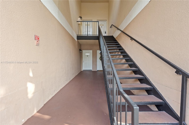 stairway featuring a towering ceiling and concrete flooring