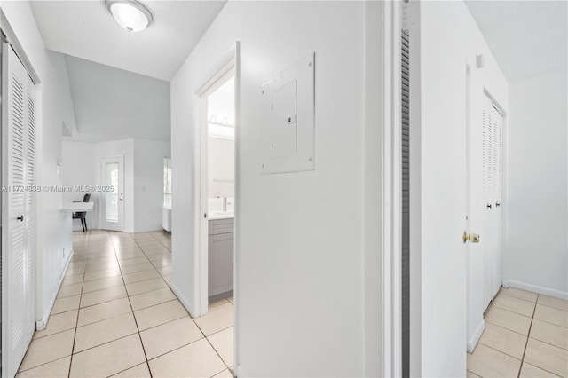 hallway featuring light tile patterned floors, a textured ceiling, and electric panel