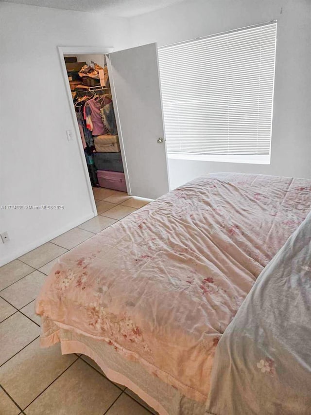 bedroom featuring a spacious closet, a closet, and light tile patterned floors