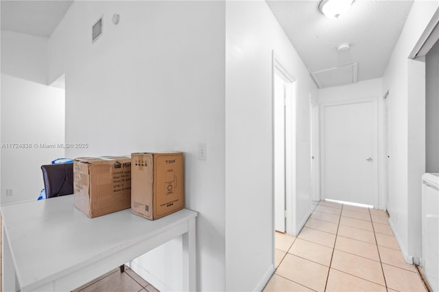 hallway featuring light tile patterned floors and a textured ceiling