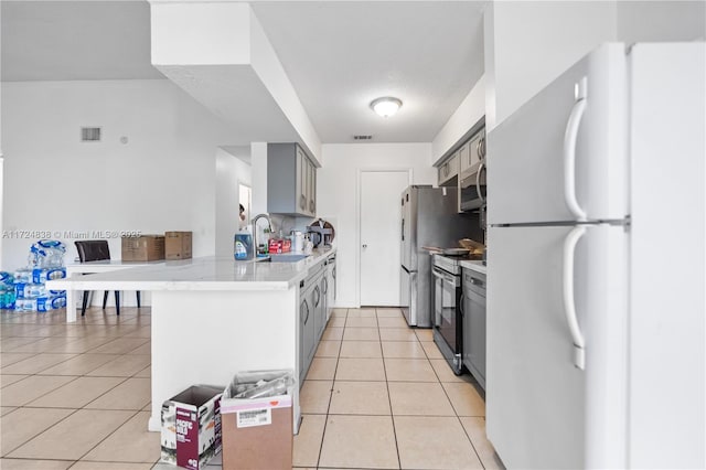 kitchen featuring light tile patterned floors, stainless steel appliances, gray cabinets, and sink