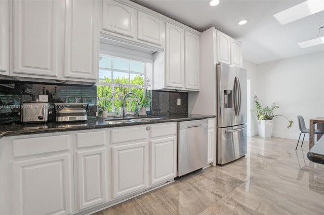 15100 SW 89th Ct, Palmetto Bay, FL 33176 - kitchen featuring dark stone counters, a sink, backsplash, a skylight, and stainless steel appliances