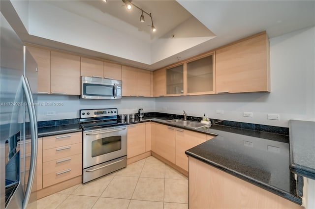 kitchen featuring stainless steel appliances, sink, light brown cabinets, light tile patterned floors, and dark stone countertops