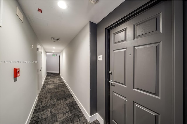 hall with dark colored carpet