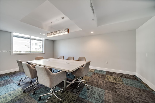 dining room with a tray ceiling and dark carpet