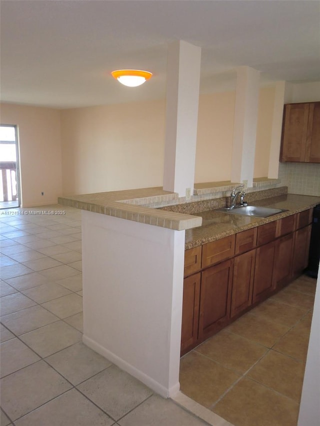 kitchen with backsplash, kitchen peninsula, sink, and light tile patterned floors