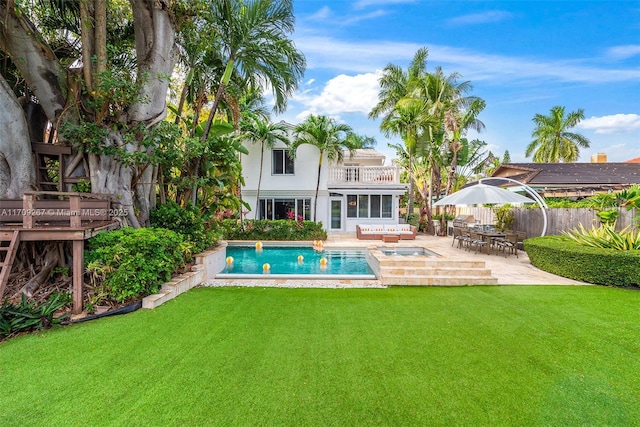 back of house with a fenced in pool, fence, a balcony, a yard, and a patio