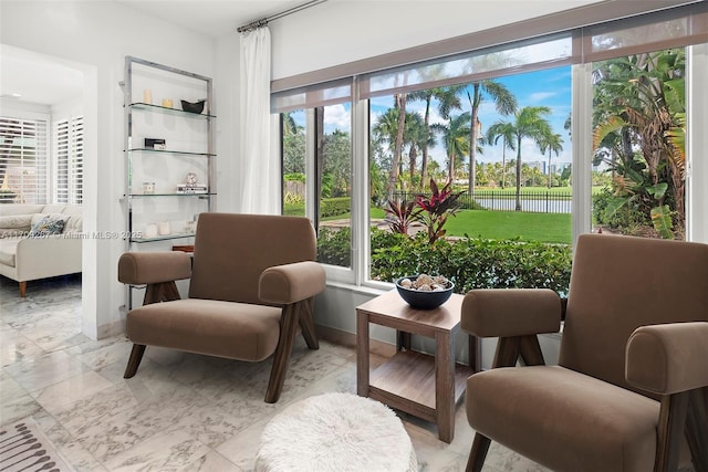 interior space featuring baseboards, marble finish floor, and a healthy amount of sunlight