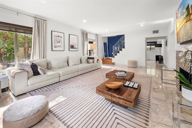 living area featuring visible vents, a fireplace with raised hearth, stairs, recessed lighting, and marble finish floor