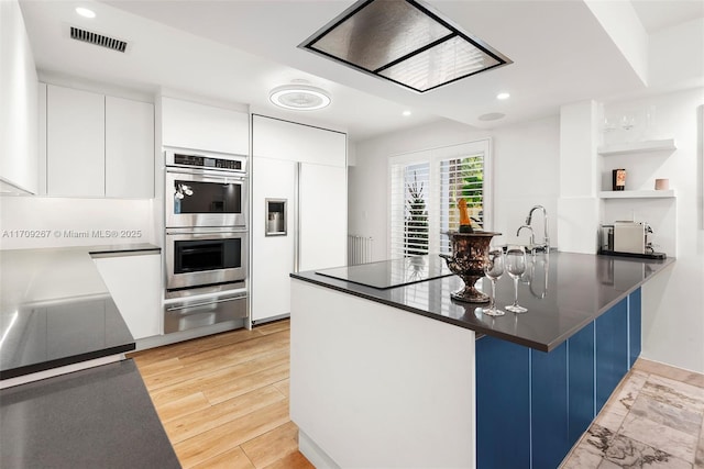 kitchen featuring paneled fridge, dark countertops, a peninsula, double oven, and a warming drawer