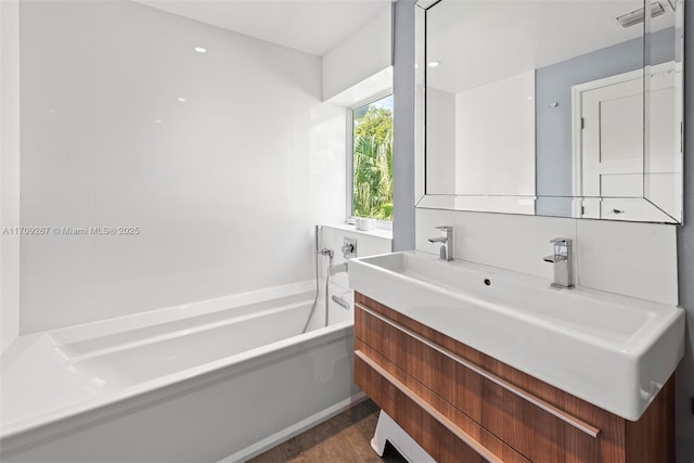 bathroom with vanity, a bath, wood finished floors, and visible vents