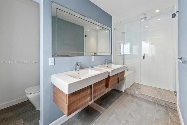 bathroom featuring toilet, a stall shower, vanity, and baseboards