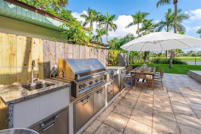 view of patio / terrace with area for grilling, a sink, a fenced backyard, grilling area, and outdoor dining area