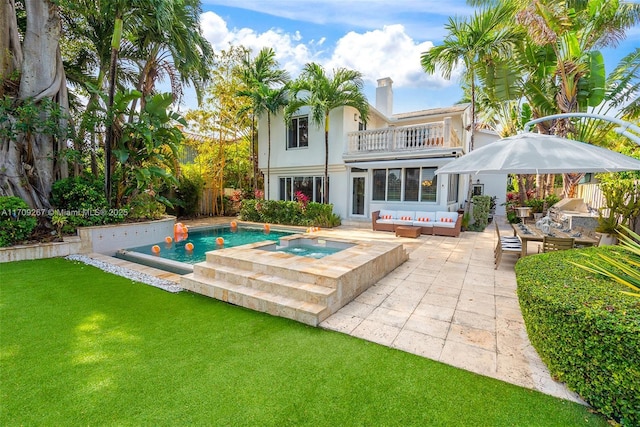 back of house with an outdoor living space, a patio, a yard, a balcony, and an in ground hot tub