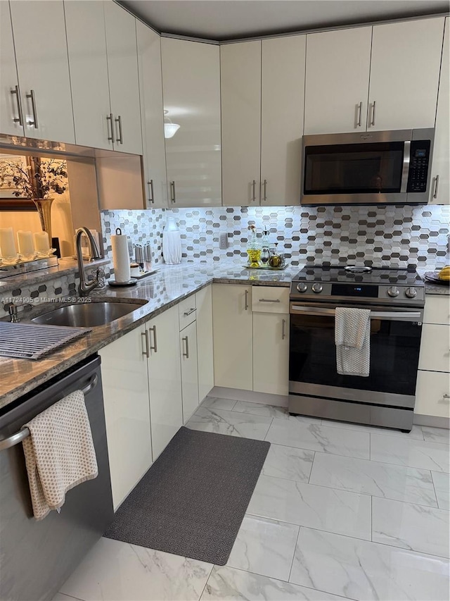 kitchen featuring tasteful backsplash, dark stone countertops, sink, and stainless steel appliances