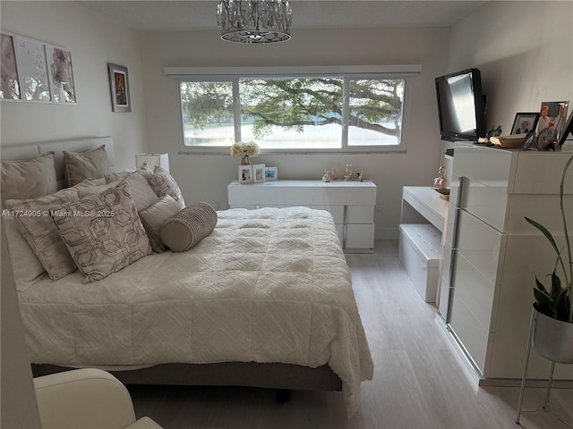 bedroom featuring an inviting chandelier and light hardwood / wood-style flooring