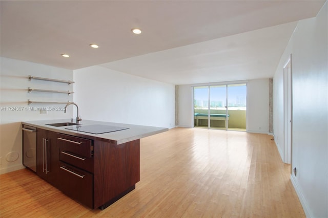 kitchen with dishwasher, black electric stovetop, sink, light wood-type flooring, and a wall of windows