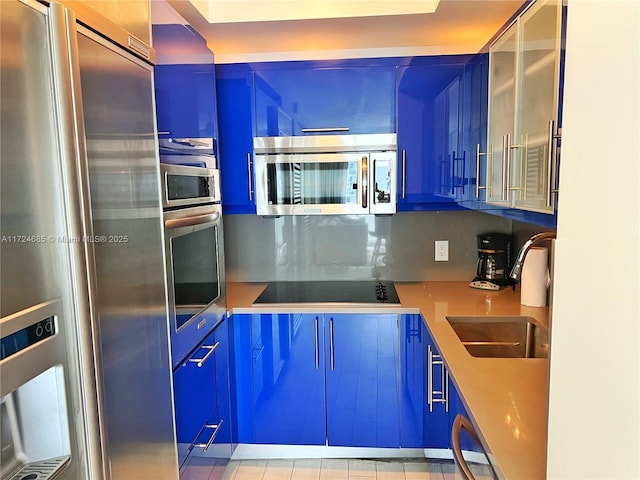 kitchen with blue cabinetry, decorative backsplash, sink, and appliances with stainless steel finishes