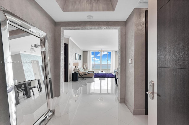 hallway featuring light tile patterned flooring, expansive windows, and an inviting chandelier