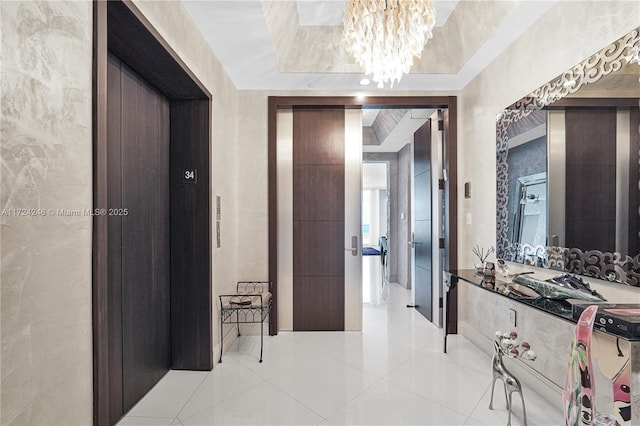 corridor with a raised ceiling, light tile patterned floors, an inviting chandelier, and elevator