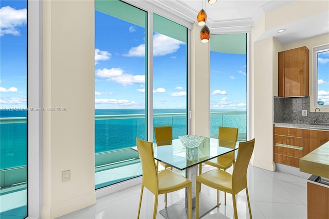 tiled dining area featuring crown molding, a water view, and sink