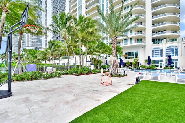 surrounding community with a lawn, a patio, a swimming pool, and basketball hoop