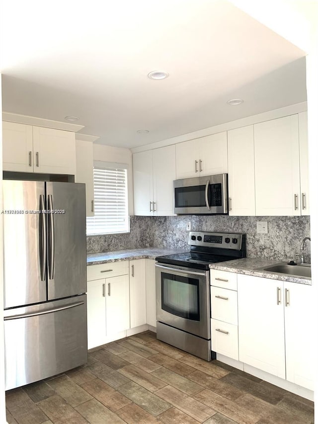 kitchen featuring backsplash, sink, white cabinets, and stainless steel appliances