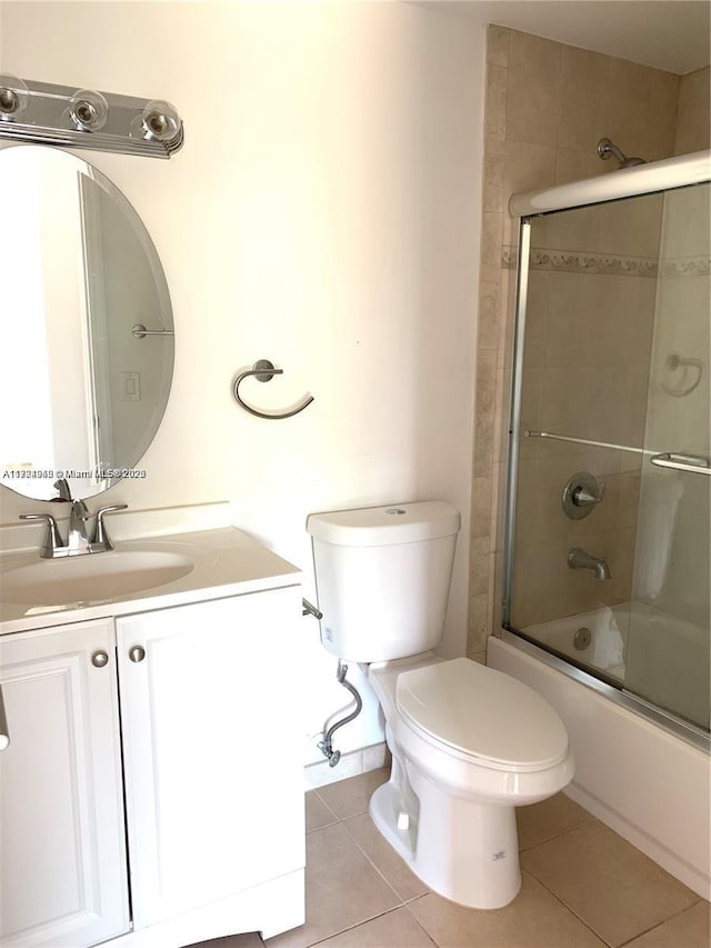 full bathroom featuring toilet, vanity, tile patterned floors, and bath / shower combo with glass door