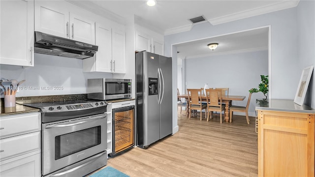 kitchen with stainless steel appliances, white cabinets, and ornamental molding