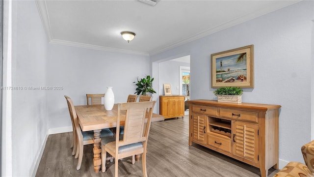 dining room with light wood-type flooring and crown molding