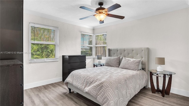 bedroom with ceiling fan, ornamental molding, multiple windows, and hardwood / wood-style flooring