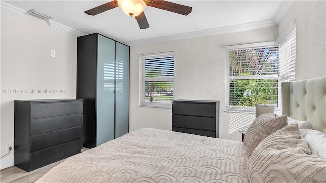 bedroom with ceiling fan, crown molding, and light hardwood / wood-style floors