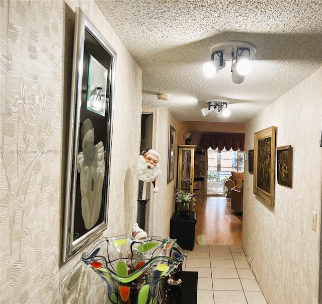 hall featuring light tile patterned floors and a textured ceiling