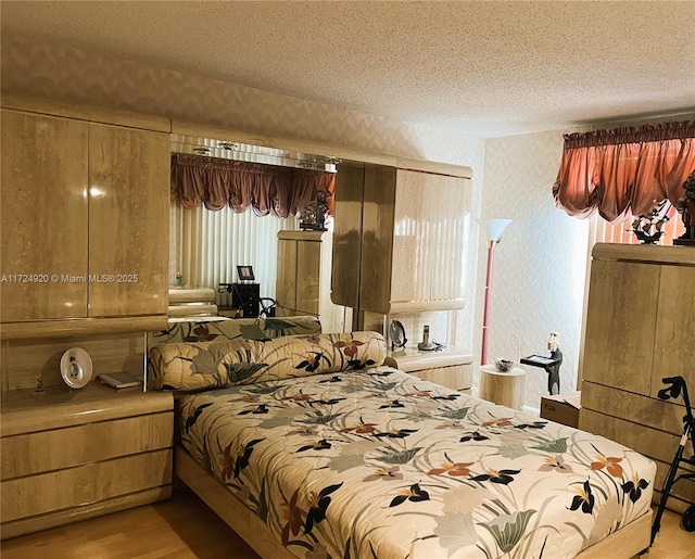 bedroom featuring multiple windows, light hardwood / wood-style flooring, and a textured ceiling