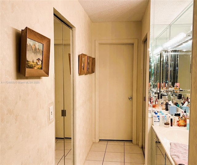 hall with a textured ceiling and light tile patterned flooring