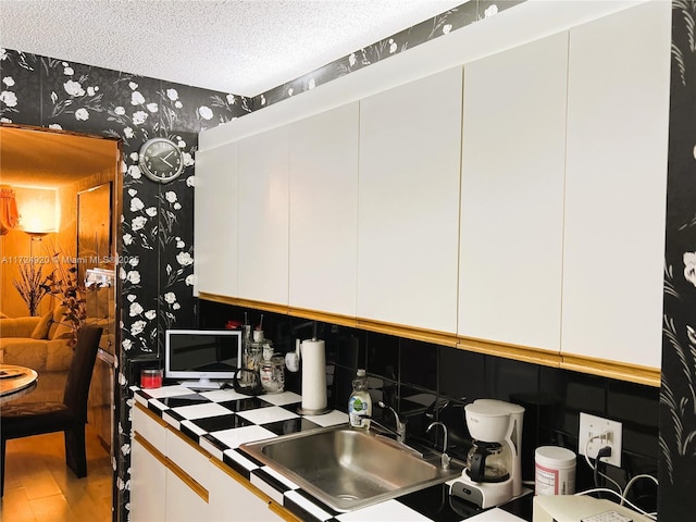 kitchen featuring a textured ceiling, hardwood / wood-style flooring, white cabinetry, and sink