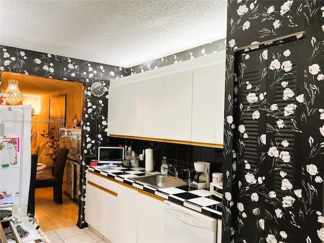 kitchen featuring white cabinetry, sink, tile countertops, a textured ceiling, and white appliances