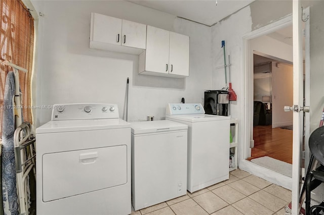 laundry area featuring cabinets, light tile patterned floors, and washing machine and clothes dryer