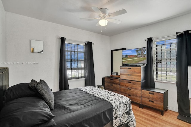 bedroom featuring ceiling fan, multiple windows, and light hardwood / wood-style flooring