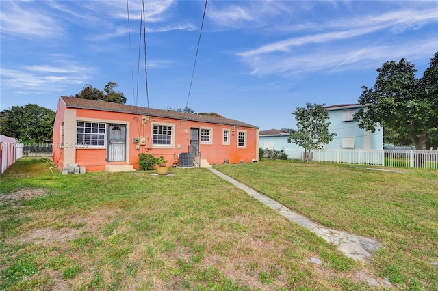 view of front of house with central AC unit and a front yard