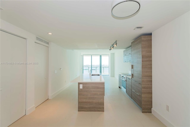 650 NE 32nd St Unit 2703, Miami, FL 33137 - kitchen featuring light countertops, modern cabinets, track lighting, a center island, and brown cabinets
