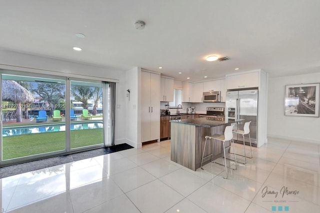 kitchen with white cabinets, sink, a breakfast bar area, a kitchen island, and stainless steel appliances