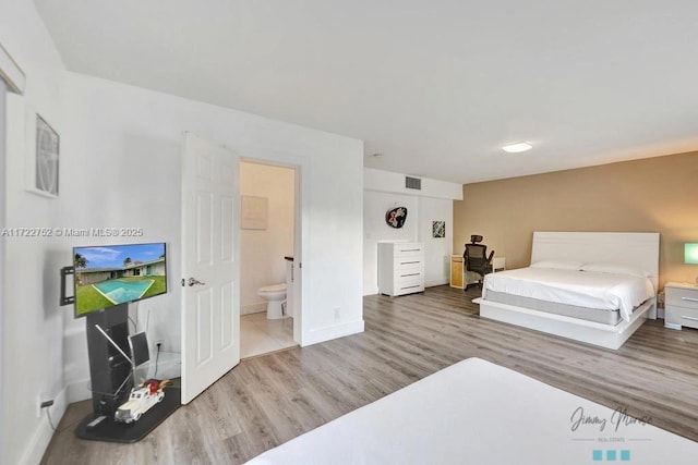 bedroom with ensuite bath and wood-type flooring