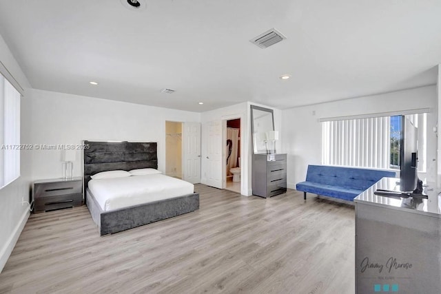 bedroom featuring ensuite bathroom, a spacious closet, and light wood-type flooring