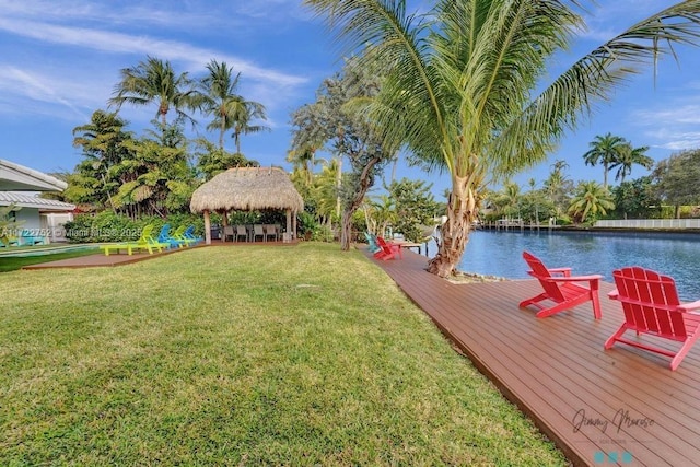 view of dock with a gazebo, a water view, and a lawn