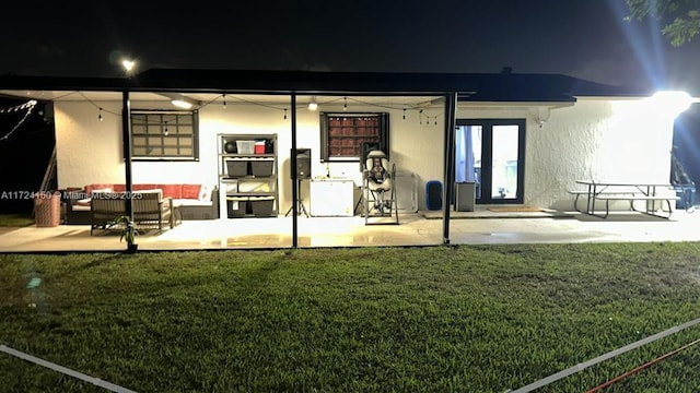 back house at night with a yard and a patio