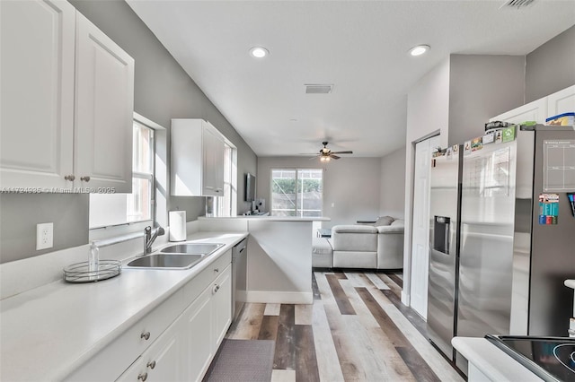 kitchen featuring appliances with stainless steel finishes, white cabinetry, sink, kitchen peninsula, and light wood-type flooring