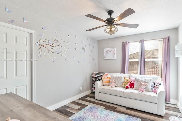 living room featuring ceiling fan, dark wood-type flooring, and a textured ceiling