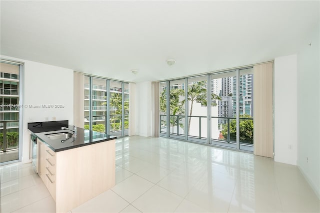 kitchen featuring dishwashing machine, light tile patterned floors, expansive windows, and sink