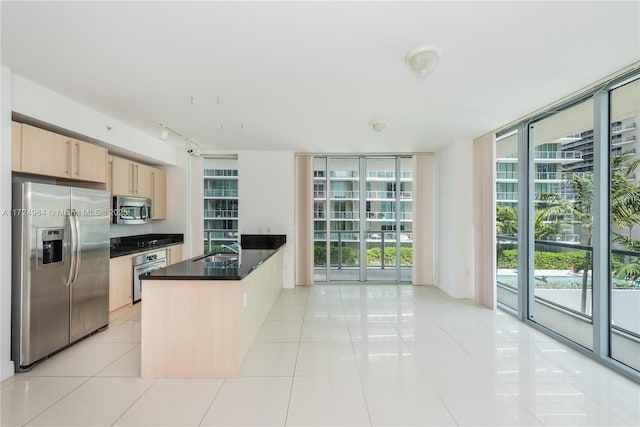 kitchen with light brown cabinetry, expansive windows, stainless steel appliances, sink, and light tile patterned floors